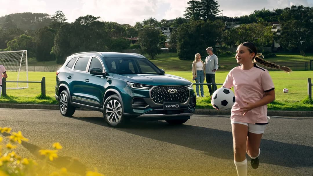 Chery Tiggo 8 Pro Max in green front three-quarter by a football field