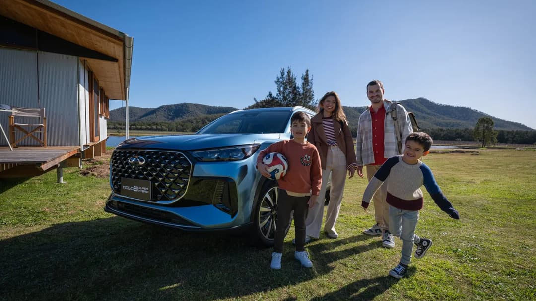 Chery Tiggo 8 Super Hybrid in blue front three-quarter with a family on a country lawn