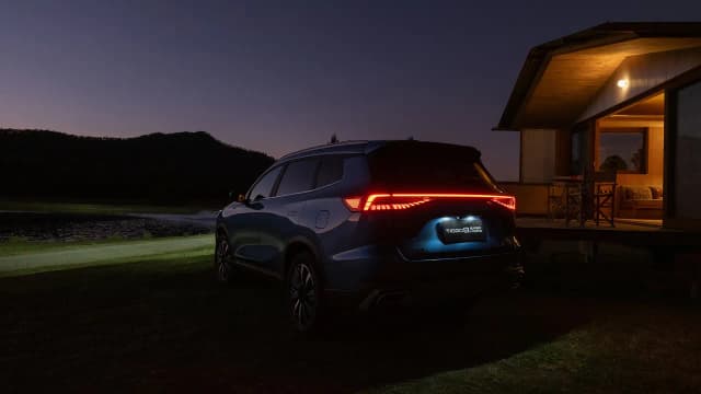 Chery Tiggo 8 Super Hybrid rear three-quarter at night by a cabin