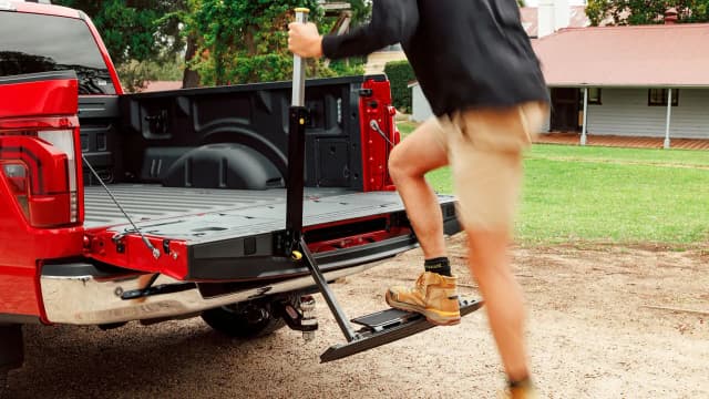 Ford F-150 tailgate step being used to climb into the tub