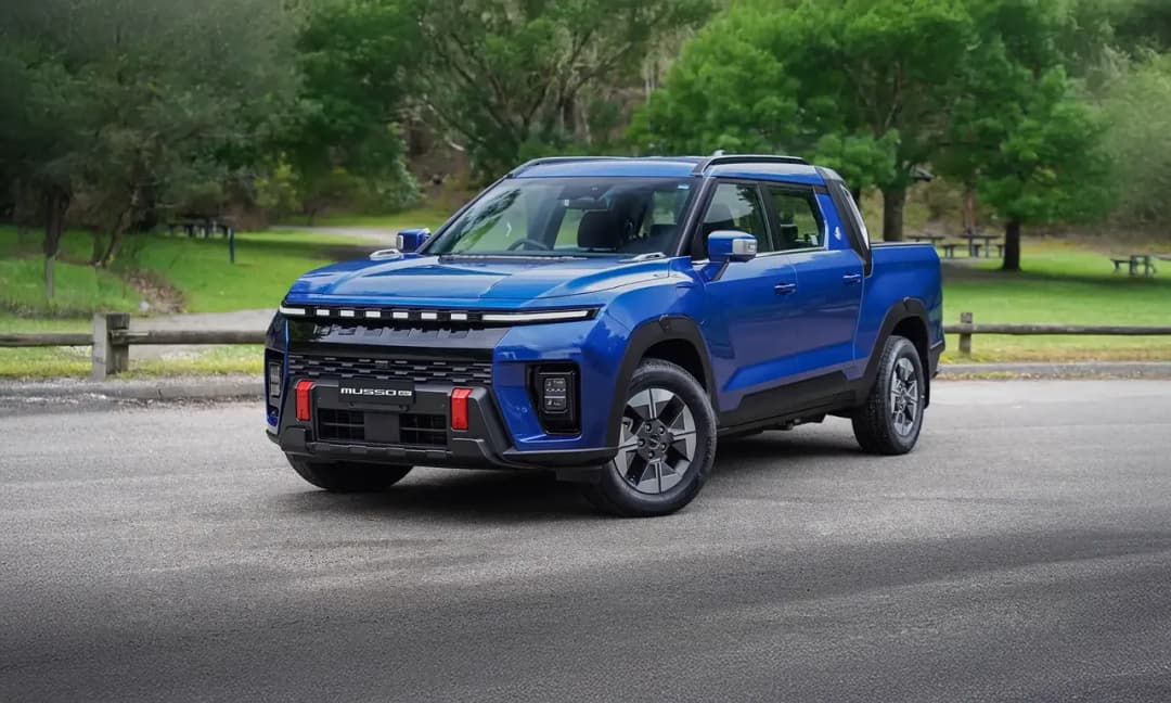 KGM Musso EV electric ute in blue, front three-quarter view in a park