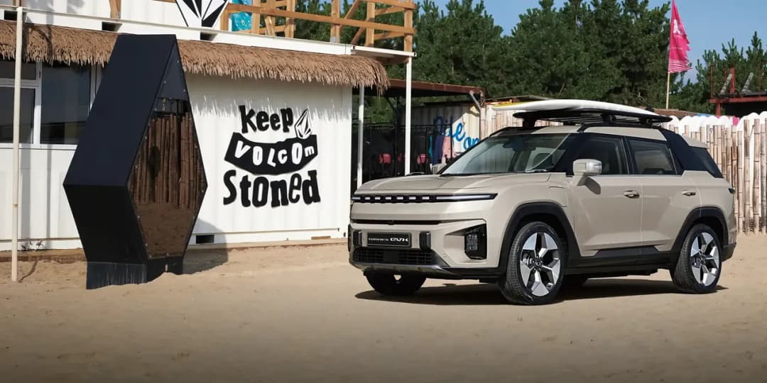KGM Torres EVX electric SUV in beige parked beside a beach shack