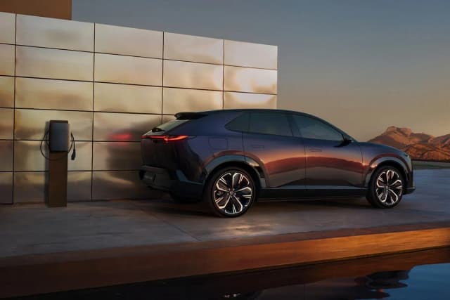 Mazda CX-6e parked beside a wall charger, rear three-quarter view