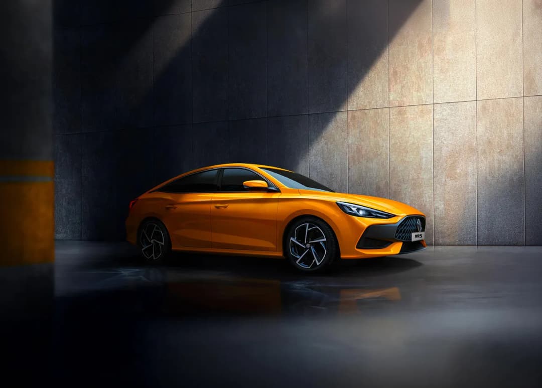 MG5 sedan in orange front three-quarter in a concrete car park