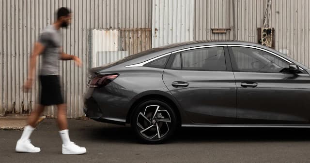 MG5 sedan in grey side profile beside a corrugated iron wall