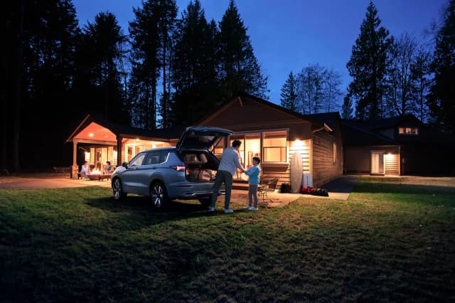 Mitsubishi Outlander with tailgate open outside a cabin at night