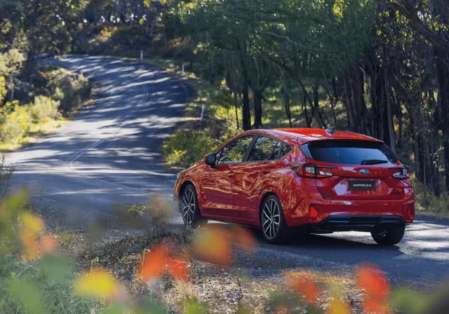 Subaru Impreza hatch rear three-quarter on a winding forest road