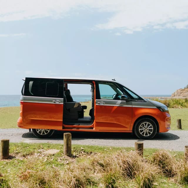 Volkswagen Multivan side view with the sliding door open on a coastal clifftop