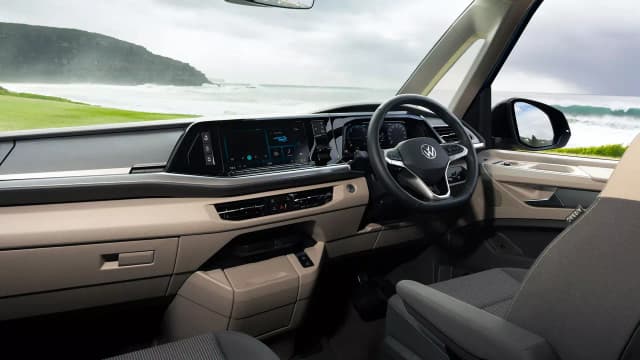 Volkswagen Multivan dashboard and front seats with a beach view through the windscreen