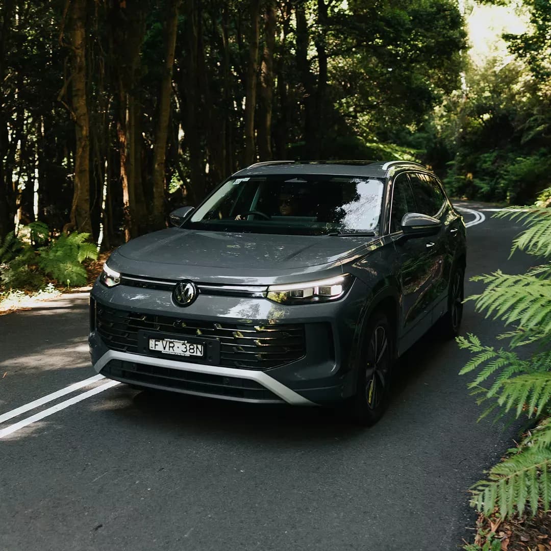 2026 Volkswagen Tayron in grey driving on a forest road, front three-quarter view