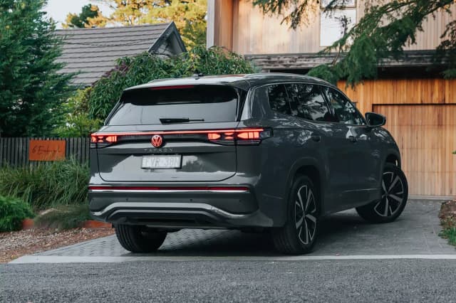 Grey Volkswagen Tayron rear three-quarter view parked in a timber clad driveway