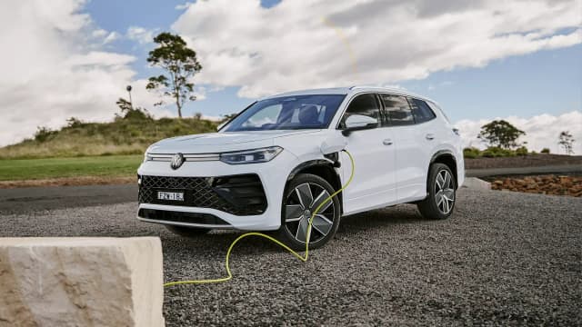 White Volkswagen Tayron eHybrid plugged in to charge on a gravel lookout