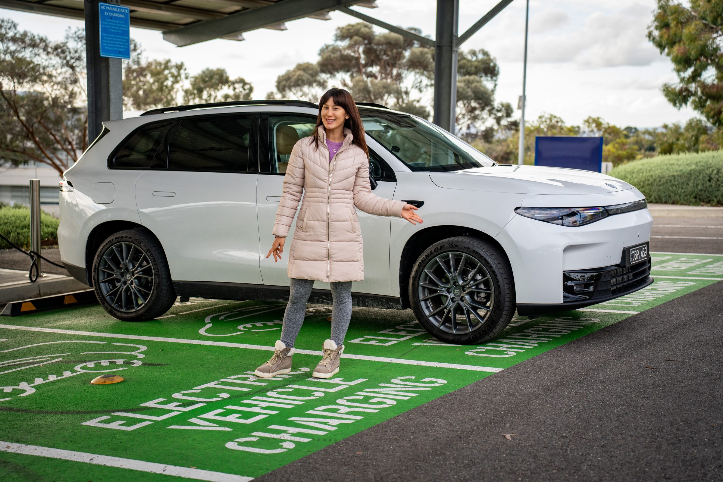 A CarTell.tv presenter with an electric vehicle at a charging bay